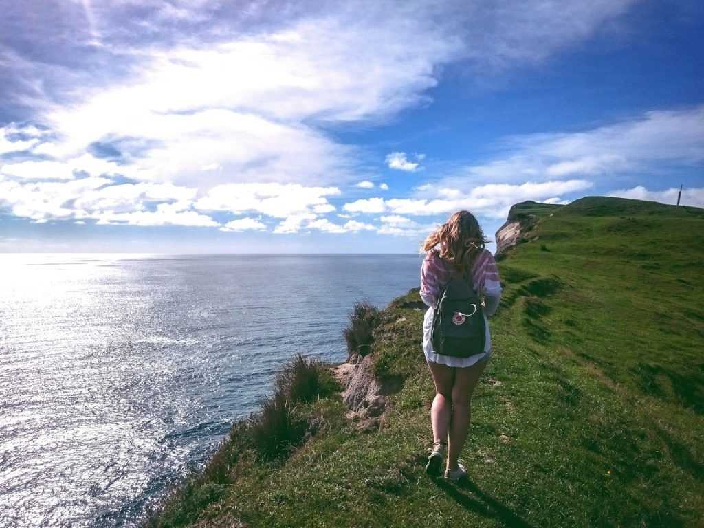 mujer alejándose andando por un acantilado.